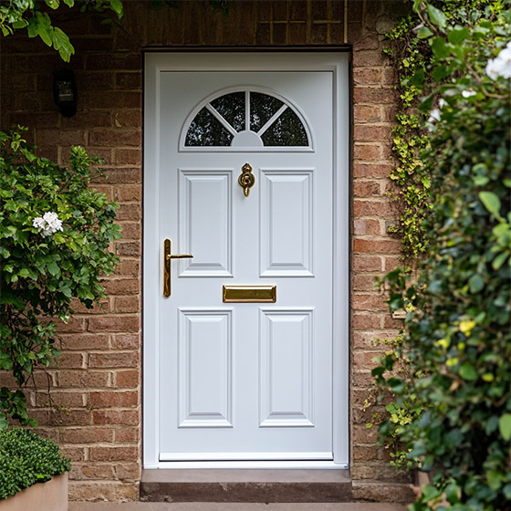 White door with gold letterbox and handle. White plants surround the pathway leading up to it.