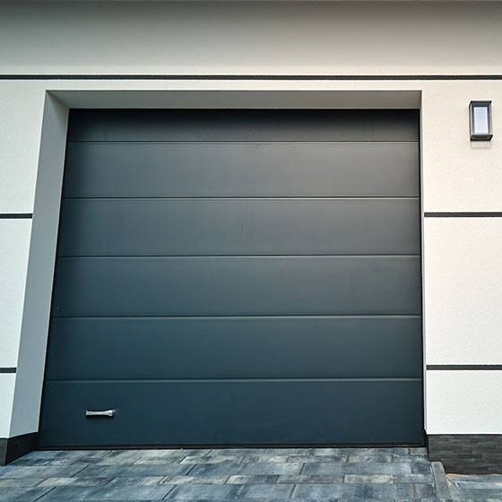 A smart, dark grey, evenly painted garage door with a silver handle at the bottom left